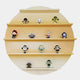Twelve unique figurines are evenly displayed on the Giant Sculptures Orbis Yellow Circular Multi-Tier Decorative Shelf, creating a vibrant focal point.