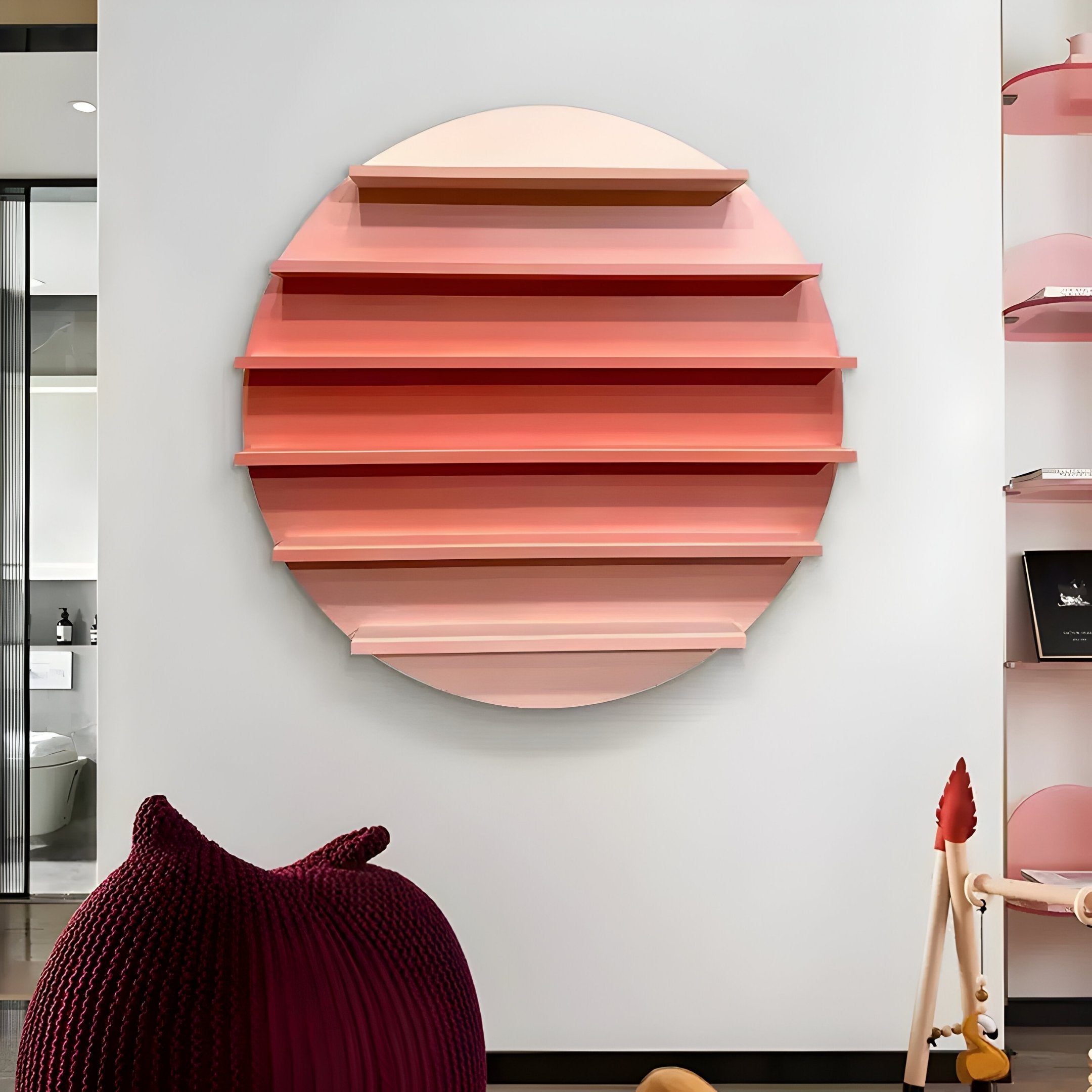 The contemporary room features a Giant Sculptures Orbis Pink Circular Multi-Tier Decorative Shelf with gradient pink and peach layers on a light wall. A dark, textured chair adds to the modern aesthetic.