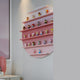 The Orbis Rose Pink Circular Multi-Tier Decorative Shelf by Giant Sculptures features four tiers showcasing colorful toy figurines. Mounted on a pale wall, a desk and lamp are visible in the foreground.