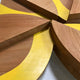 The Lignos Yellow Accent 3D Wall Art by Giant Sculptures is a wooden sculpture with overlapping geometric shapes resembling slices of pie or citrus, featuring a natural wood and yellow finish with a sleek leaf motif and smooth edges.