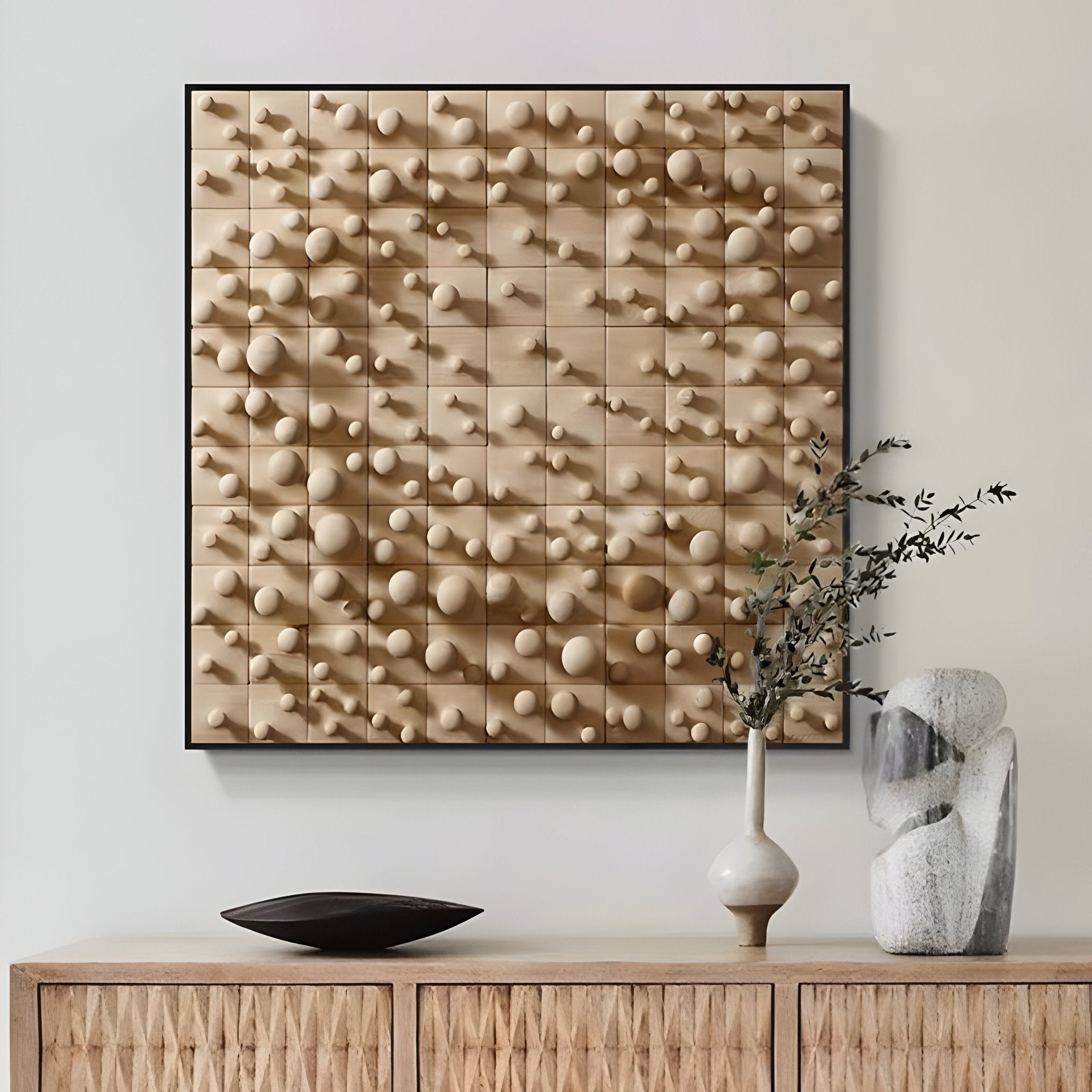 Mounted above the wooden cabinet is the Orbila Wooden Spheres Dynamic 3D Wall Art With Frame by Giant Sculptures. On the cabinet sit a small tree branch in a white vase, a sculpted stone object, and a shallow black bowl, creating a harmonious blend of modern design elements.