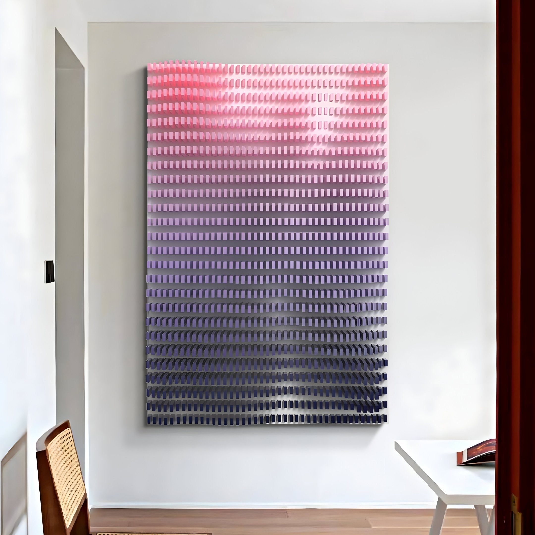 The Wavluxe Gradient Pink & Purple Wood Mosaic Vertical 3D Wall Art from Giant Sculptures is a stunning piece featuring small rectangles shifting from pink to blue. Mounted on a white wall in a modern room, it complements the wooden chair and white table with its sleek design.