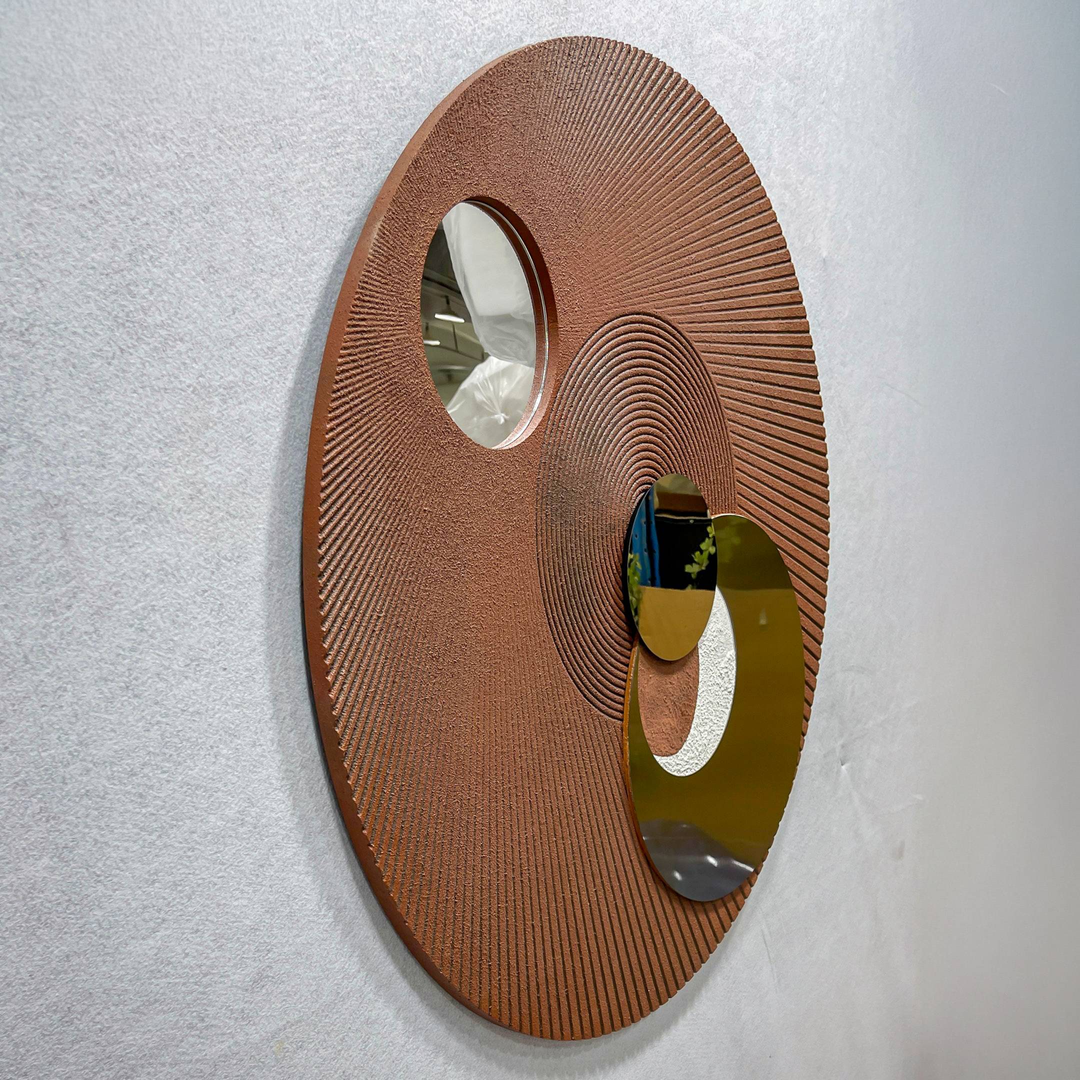 Orbitra Copper Reflective Circular 3D Wall Art shown at an angle, featuring two polished copper-toned mirrored discs on a ridged textured brown panel.