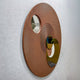 Orbitra Copper Reflective Circular 3D Wall Art shown at an angle, featuring two polished copper-toned mirrored discs on a ridged textured brown panel.