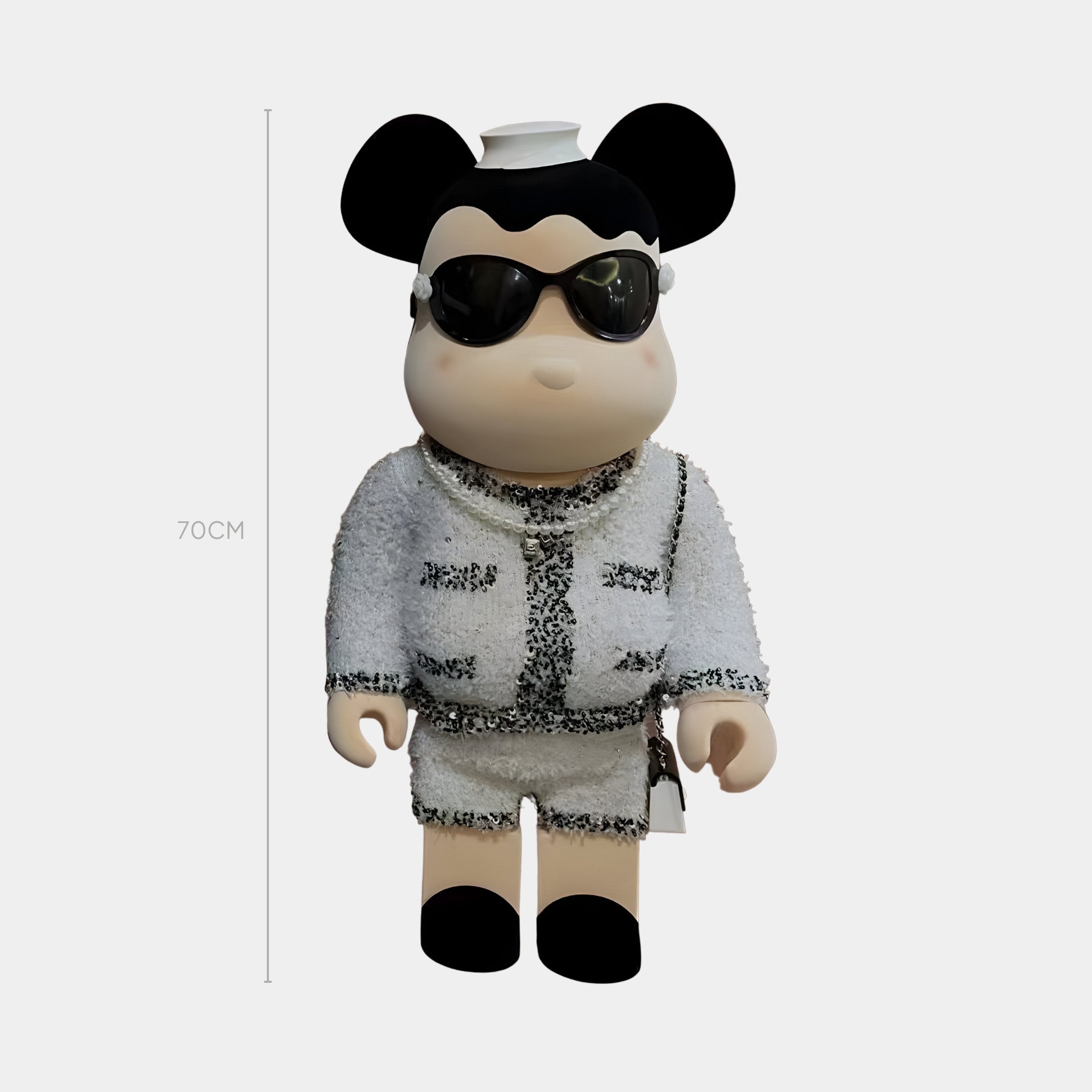 The White Couture Bear Sculpture - 70cm by Giant Sculptures features round black ears, a beige face and hands, a bouclé-inspired white outfit with black trim, sunglasses, and a small white hat for a chic cartoon style.