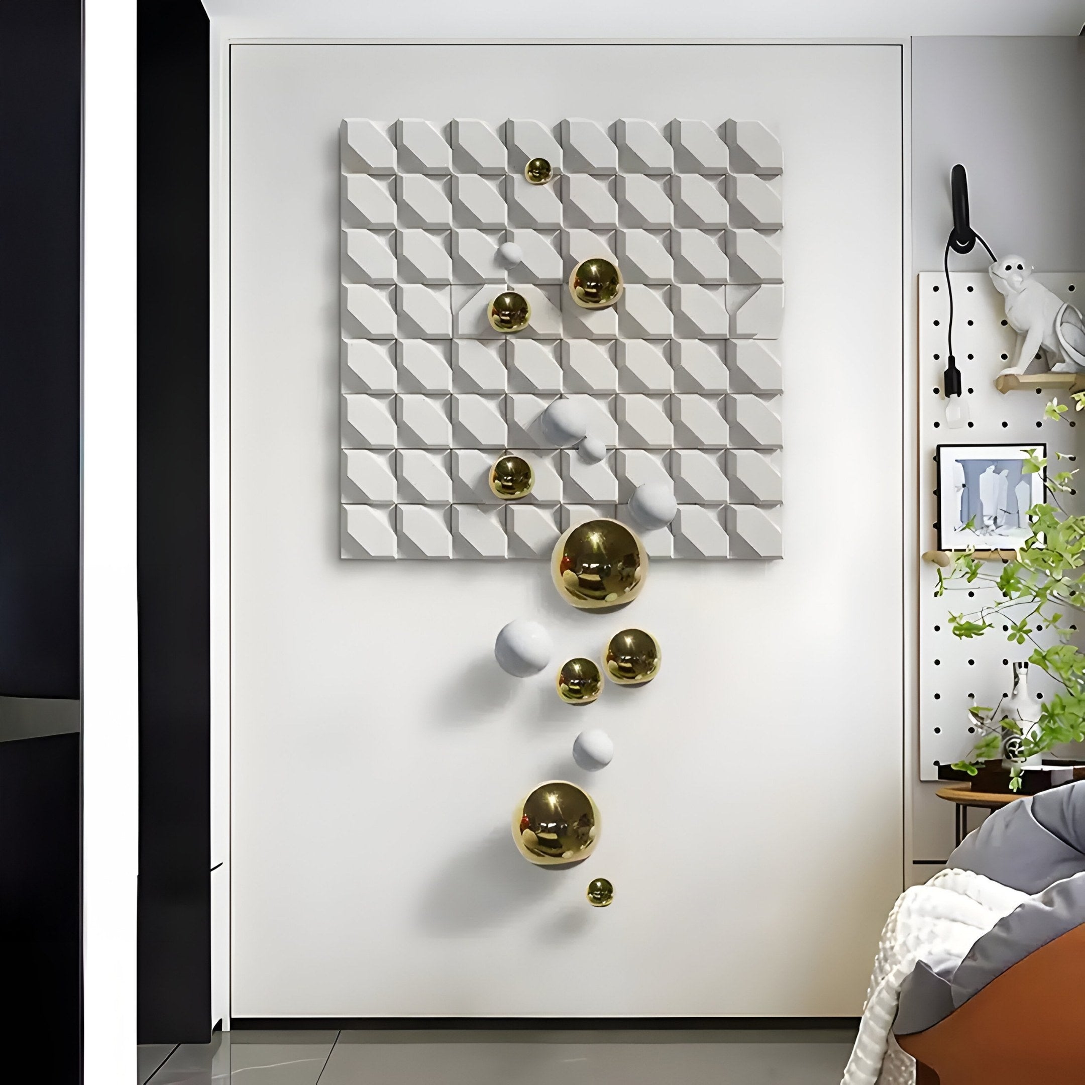 The Orbina White 3D Wood Relief Wall Art by Giant Sculptures is perfect for a modern bedroom, featuring a white geometric textured panel and gold and white metal spheres. It pairs beautifully with contemporary décor, including a bed with white covers and a plant.