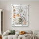 A modern living room features a white sofa with green and mustard pillows. Hanging on the cream wall is the Florere Botanical Harmony, a large hand-painted artwork by Giant Sculptures. The pieces spherical white accents add texture to the decor.