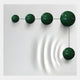 The Galactica White Wood Relief 3D Wall Art With Linear Green Metal Ball by Giant Sculptures features five shiny green metal balls on a white wall, connected by a black line, with wave-like patterns under the largest sphere for a striking 3D effect.