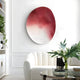 A modern living room features Giant Sculptures Fluctus Red Textured Sandstone Wood Relief 3D Wall Art on a white wall. Below it, a white curved sofa offers comfort, while a glass coffee table with a figurine and vase of white flowers complements the lush greenery from surrounding plants.