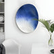 The Fluctus Blue Textured Sandstone Wood Relief 3D Wall Art by Giant Sculptures, with its swirling gradient from blue to white, enhances the modern minimalistic rooms vibe, perfectly complementing the sleek white chair and potted plant.