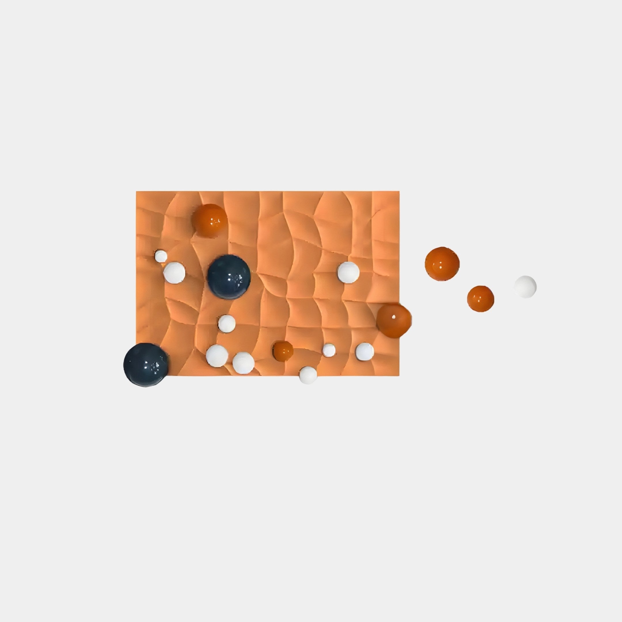 The Orbison Terracotta 3D Wood Relief Wall Art With Floating Metal Ball by Giant Sculptures showcases a textured rectangular orange surface with various black, white, and orange spheres extending onto a white background, perfect for modern interior décor enthusiasts.