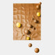 The Orbison Brown 3D Wood Relief Wall Art With Floating Metal Ball by Giant Sculptures features a brown textured surface with raised yellow and brown bumps and floating metal spheres, ideal for adding a modern touch to interiors.