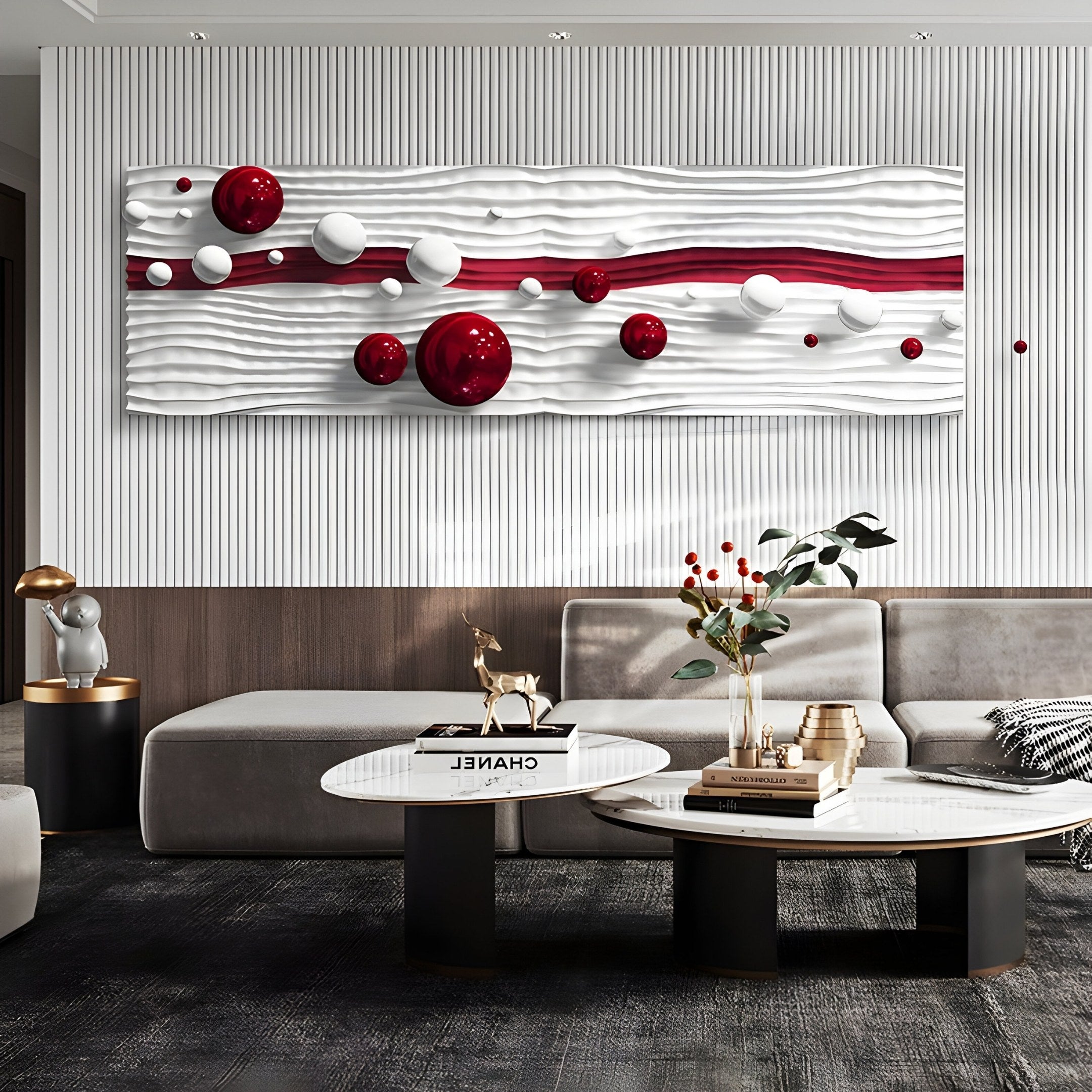 A modern living room features the Lustra Red & White 3D Wood Relief Wall Art by Giant Sculptures, showcasing red and white spheres on wavy panels. A gray sectional encircles two round coffee tables with books and decor, while a small sculpture is placed on a gold-accented side table.