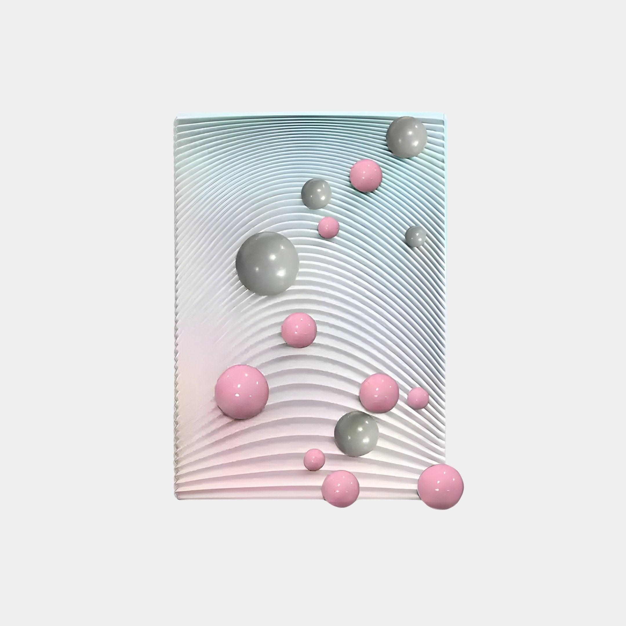 The Sphera Gradient 3D Wood Relief Wall Art by Giant Sculptures features a white textured backdrop with curved patterns, adorned with grey and pink metal balls, offering depth and motion in this striking contemporary piece.