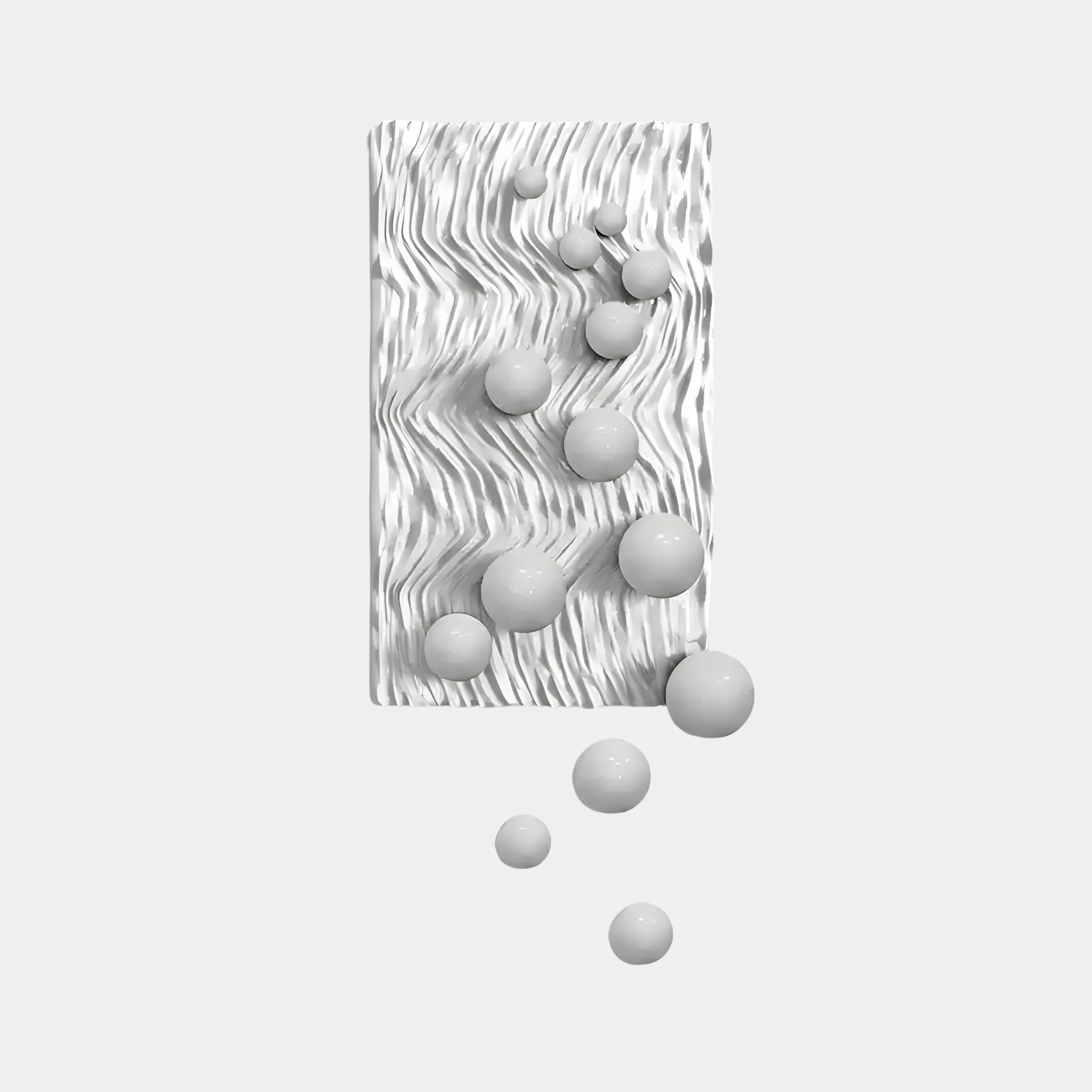 The Fluxion White 3D Wood Relief Wall Art With Metal Ball by Giant Sculptures is a minimalist masterpiece featuring a textured white vertical surface with smooth, varying spheres that seamlessly blend into the background.