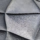 The Orbita 6-Set Circular Neutral Grey 3D Wood Relief Wall Art by Giant Sculptures features a textured metallic look with geometric folds, where angular ridges shift from dark to light gray, offering a solid and reflective pattern perfect for interior decoration.