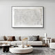 A modern living room showcases a neutral-toned sofa with assorted pillows, a textured coffee table, and is highlighted by the Elytrum White Hand-Painted Wood Relief 3D Wall Art by Giant Sculptures. Decorative objects and a plant in vases complete the stylish minimal décor.