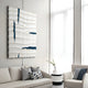 In a modern minimalist living room, a white sofa and armchair with gray cushions and blue accents set the scene. Above, the Striata White & Blue Wood Carving 3D Wall Art by Giant Sculptures adds dimension. A small round table with a white vase sits between the seating.
