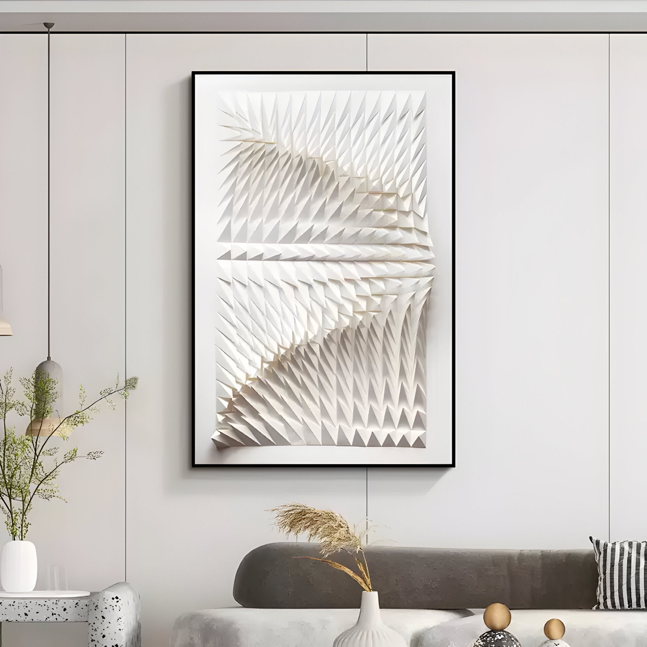 A modern living room features Giant Sculptures Elorium White Facet Hand-Painted Wood Relief 3D Wall Art, highlighting white triangular patterns. A beige sofa with monochrome cushions and a textured round side table adorned with greenery and dried grass completes the decor.