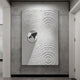 The Giant Sculptures Ondella Silver Ripple III Sandstone Wood Relief 3D Wall Art portrays concentric circles like ripples with a shiny metallic accent on a textured white surface, set against a gray backdrop.
