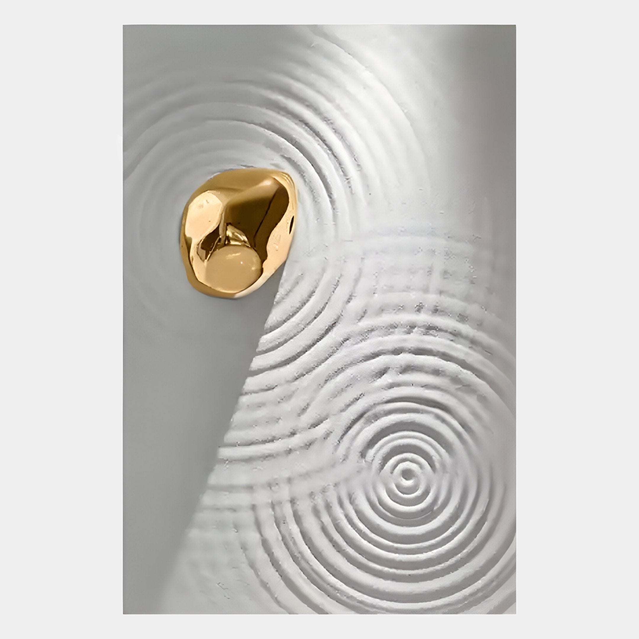 A shiny gold pebble rests on a textured white surface with concentric ripples, evoking the Ondella Gold Ripple I Sandstone Wood Relief 3D Wall Art by Giant Sculptures.