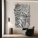A modern, minimalist room showcases the Calidora Abstract Contour Textured 3D Relief Wall Art by Giant Sculptures, with fluid lines and folds. A gray armchair pairs with a cylindrical side table on wooden flooring. Natural light enhances the serene ambiance while the wall art adds depth.