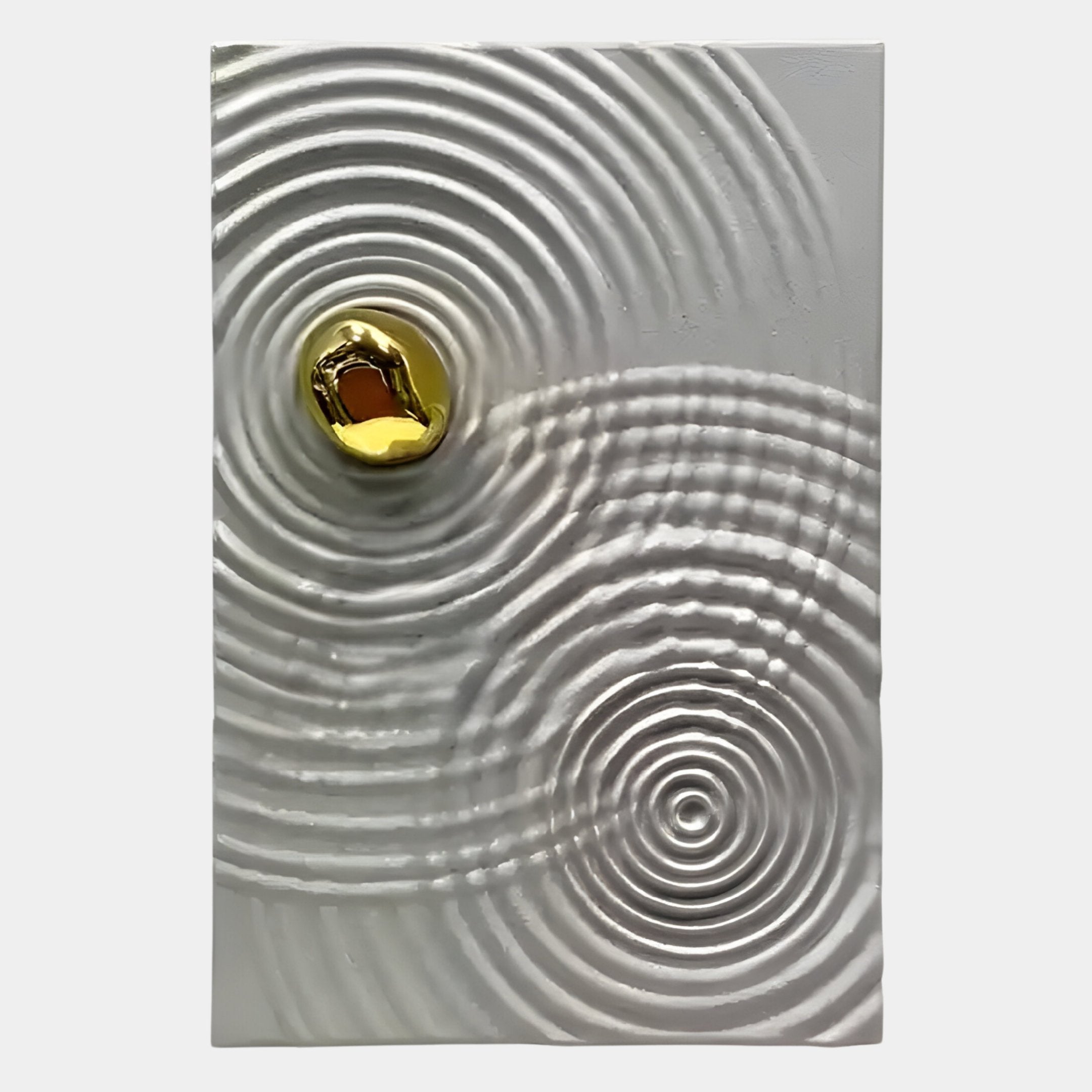 A gold, irregularly shaped object rests on a textured white surface with radiating rings—an eye-catching Calidora Golden Ripple Textured 3D Relief Wall Art by Giant Sculptures that exudes modern luxury.