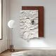 The Calidora Terra Sculpted Textured 3D Relief Wall Art by Giant Sculptures features a metallic sphere on a textured white panel against a brown background, paired with a minimalist floor lamp with a round white shade, embodying modern art aesthetics.