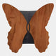 The Giant Sculptures Lucerna Teak Butterfly Wood Carving 3D Wall Art features a symmetrical butterfly shape with smooth, rounded edges, a dark center strip, visible wood grain, and intricate 3D carving details.