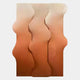 The Mystique Orange Fabric Abstract Wood Relief 3D Wall Art by Giant Sculptures features three vertical wood panels with wavy edges and warm gradient tones, from light cream to earthy orange, set against a plain backdrop.