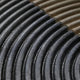 Close-up of the Artura Beige & Black Hand-Painted 3D Relief Wall Art by Giant Sculptures, showcasing parallel curved black and metallic ridges with a shiny, reflective surface—an elegant display of minimalist design.