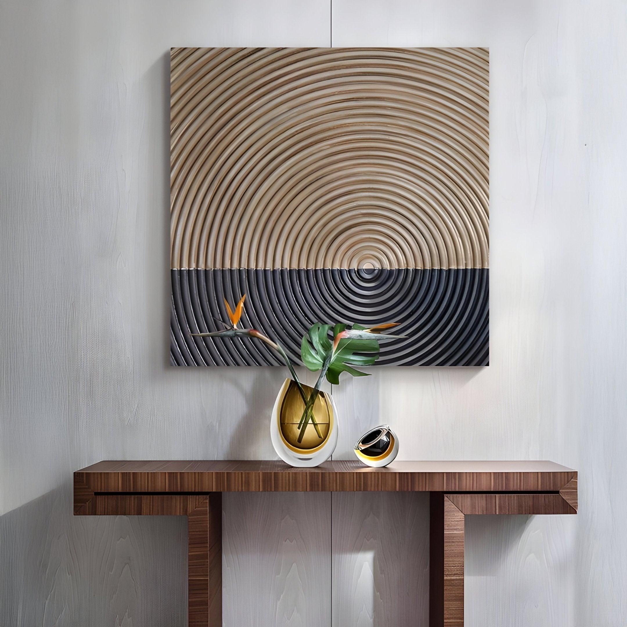A modern console table with a yellow vase of green leaves and orange flowers sits below the Giant Sculptures Artura Beige & Black Square Hand-Painted 3D Relief Wall Art. A small decorative object adds sculptural elegance beside the vase.