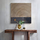 A modern console table with a yellow vase of green leaves and orange flowers sits below the Giant Sculptures Artura Beige & Black Square Hand-Painted 3D Relief Wall Art. A small decorative object adds sculptural elegance beside the vase.