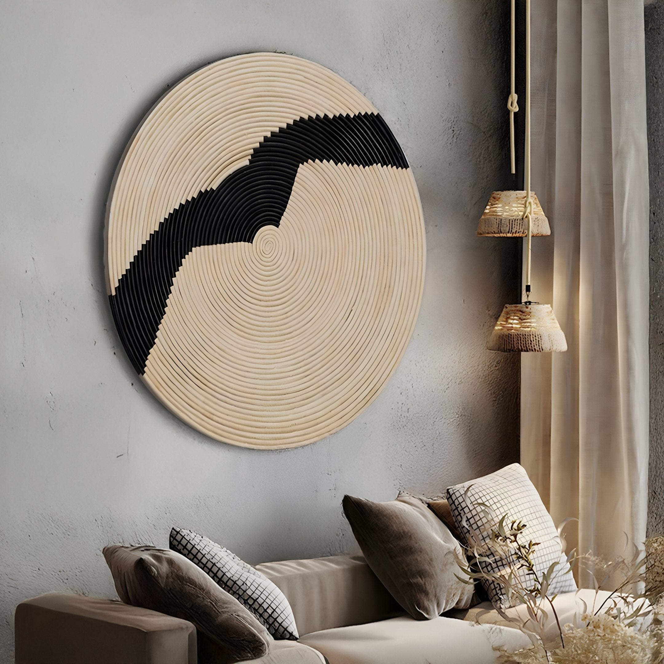 A modern living room features neutral cushions, textured beige walls, woven pendant lights, and the Giant Sculptures Artura Ivory Round Hand-Painted 3D Relief Wall Art with concentric patterns and a bold black zigzag.