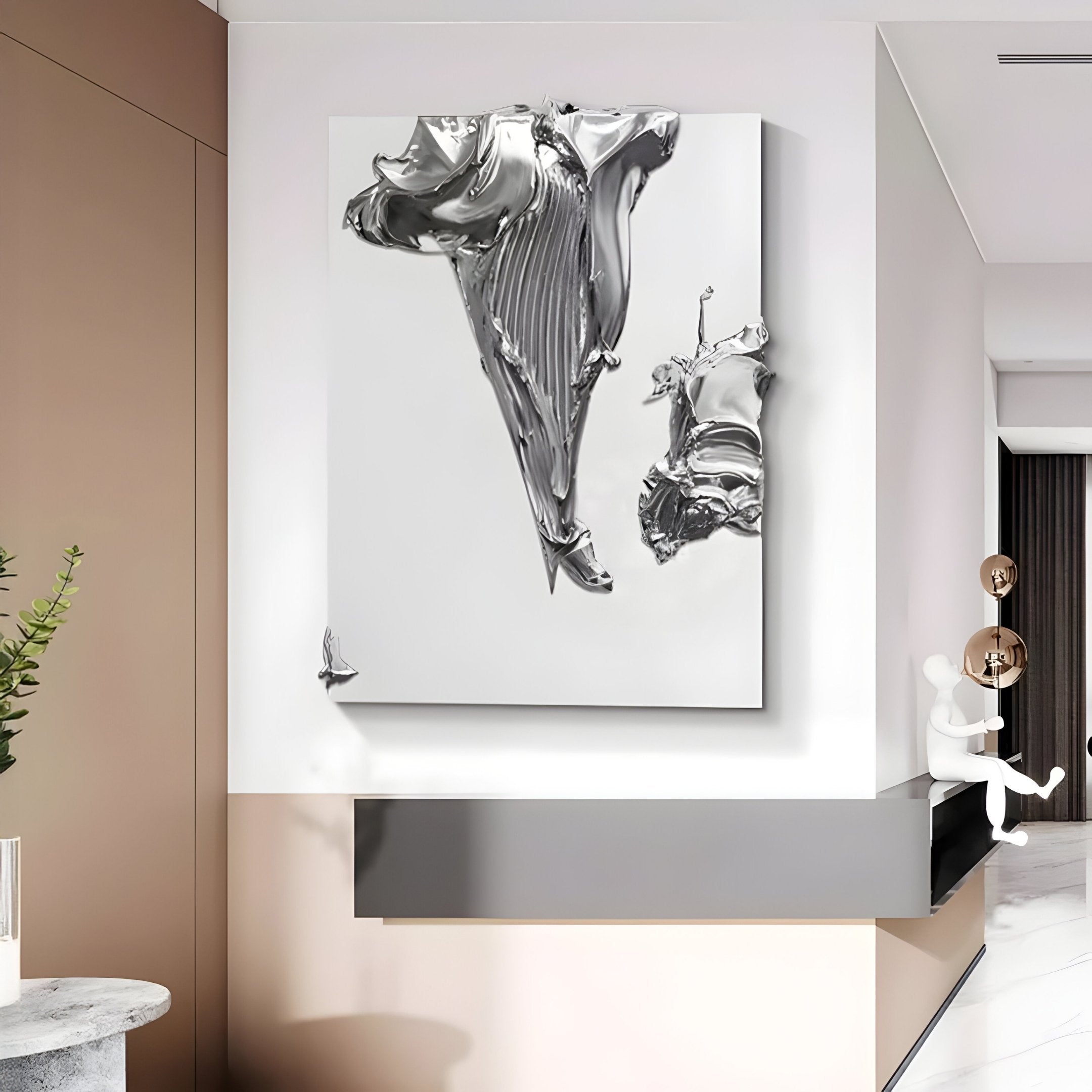 A modern hallway showcases the Opulina White & Silver II Wood Relief 3D Wall Art by Giant Sculptures on a taupe wall above a sleek gray shelf, complemented by a green plant in a vase placed on a round marble table.