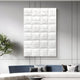 A modern living room features the Vellura White Textured Wood Relief 3D Wall Art by Giant Sculptures above a blue and white sofa with assorted pillows; Minimalist Abstraction is accentuated by a green plant on the left.