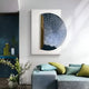A modern living space with a gray-blue sofa, green and blue cushions, a small glass of water, and a plant. The wall showcases Giant Sculptures’ Artevia Blue & White Geometric Wood Relief 3D Wall Art with gold accents.