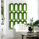 A modern living room with a white curved sofa, glass coffee table, vase of foliage, and the Giant Sculptures Revela White & Green Geometric Wood Relief 3D Wall Art—a bold touch of contemporary décor.