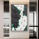 The Prosper Black & Green Metallic Fish 3D Relief Wall Art by Giant Sculptures features jagged black and green shapes on a white background with curved, gold leaf-like elements, adding elegance and artistry to a modern room with glass walls and minimalistic furniture.