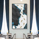 The Prosper Black & Blue Metallic Fish 3D Relief Wall Art by Giant Sculptures, featuring dark, jagged shapes like a flowing river with golden leaves on a white background, is mounted between blue curtains in an elegantly contemporary dining room.