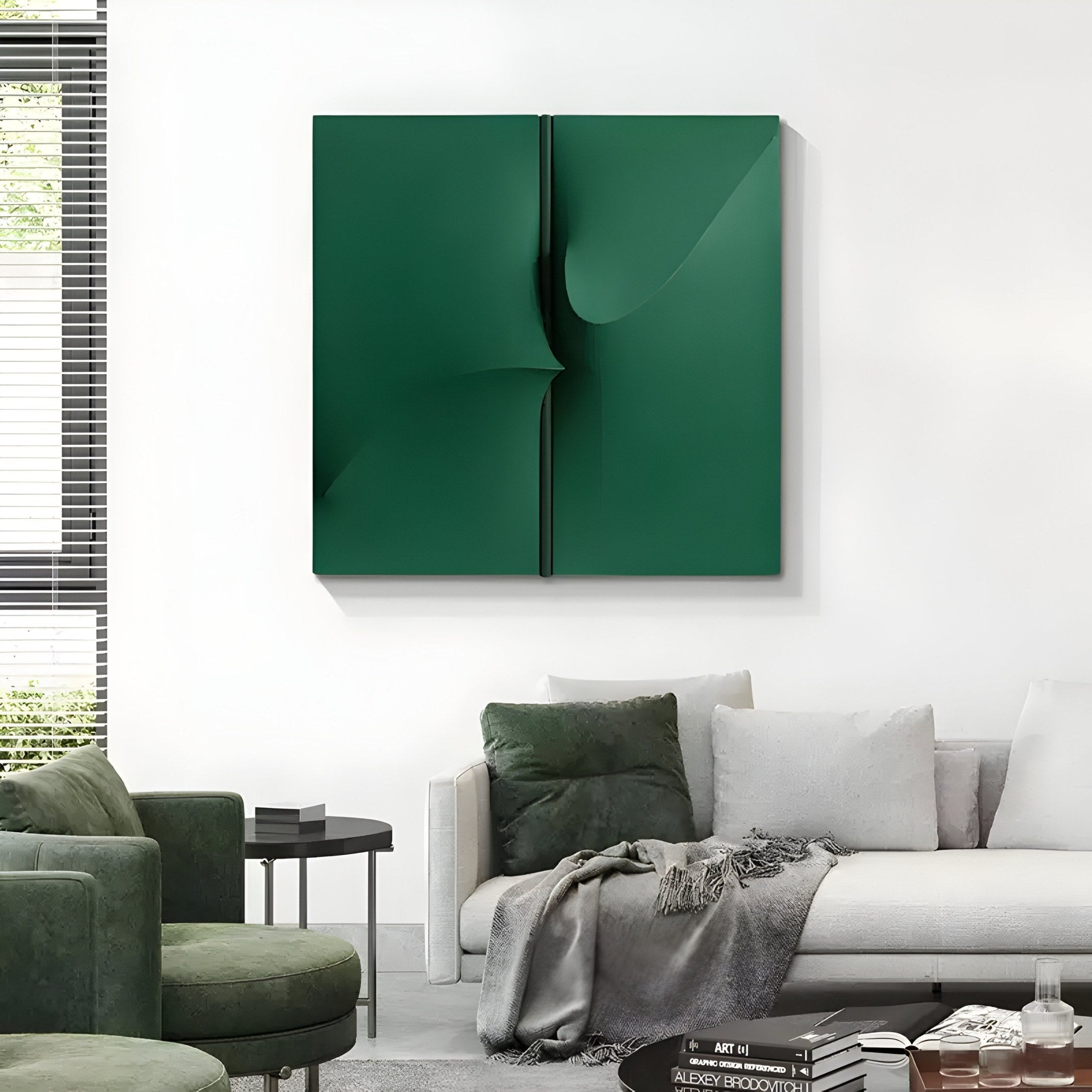 A modern living room showcases a gray sofa and green armchair with cushions, highlighted by the Delinea Green Stretch Fabric 3D Wood Relief Wall Art from Giant Sculptures above. A small table holds books and accessories, while partially opened large window blinds reveal greenery outside.