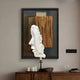 The Visagio Hand-Painted Wood Relief 3D Wall Art by Giant Sculptures features abstract wooden layers with a sculpted profile face. Beneath, a wooden sideboard holds a candle and glassware, while black light switches enhance the room’s Wabi-Sabi feel.