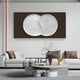 A modern living room showcases the Artivio Dark Brown & White Wood Relief 3D Wall Art by Giant Sculptures, complemented by two white sofas around a round coffee table. Subtle lighting and earth-tone accents enhance the cozy, minimalist ambiance.