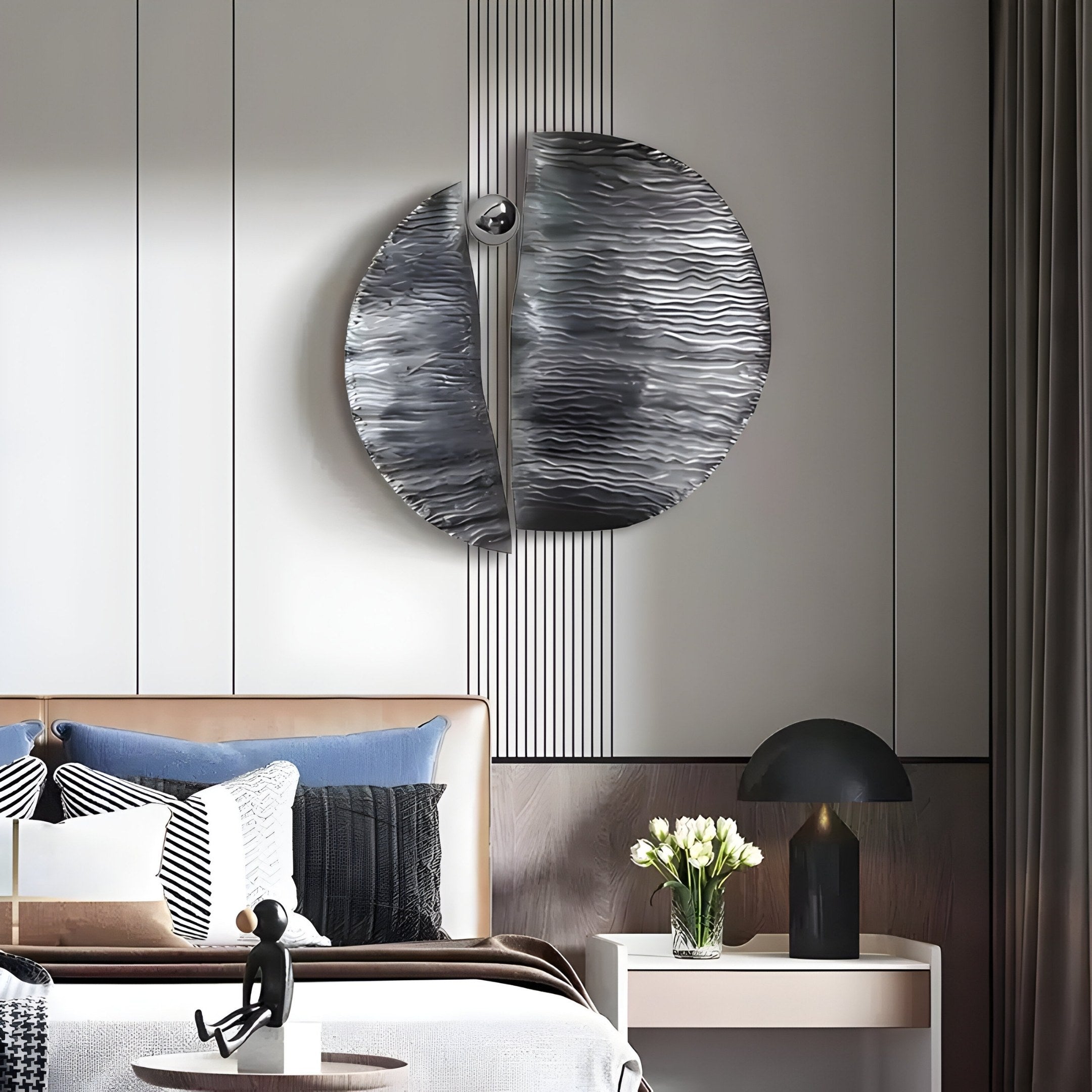 A modern bedroom includes a brown leather headboard, gray bedding, and decorative pillows. Above is Giant Sculptures Argentum Textured Wood Relief 3D Wall Art With Silver Metal Ball. A black lamp and white flowers on the bedside table complete the contemporary look.