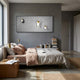 Modern bedroom with a neatly made bed, beige and pink bedding, books by the bed, gold lamps, and Giant Sculptures’ Astravera Lunar Crew Grey Textured Astronaut 3D Wall Art—showcasing three astronauts on a moon-like background.