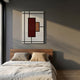 Minimalist bedroom with a wooden bed, neutral bedding, and the Gridoria Deep Red & Sand Linear Block Woven Wall Art by Giant Sculptures on a gray wall. Sunlight from a large window casts soft shadows across the room.