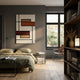 A modern bedroom with neutral tones, a low bed, Gridoria Rust & Taupe Linear Block Woven Wall Art by Giant Sculptures above the headboard, a side table with books, natural light from the window, a brown chair, and a bookshelf with decor and a lamp.