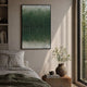 A cozy, sunlit bedroom features a bed with a green blanket and pillows. Above the bed hangs the Gridelle Forest Fade Gradient Grid 3D Paper Wall Art by Giant Sculptures. By the window, a textured table holds a ceramic vase with leafy plant.