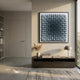 A modern minimalist living room features the Gradisect Steel Blue Fade Geometric 3D Wooden Wall Art by Giant Sculptures above a low wooden console with a lamp and vase of dried grasses, a neutral rug, bookshelves, and sunlight streaming through the window.