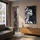 A modern living room with a gray sofa, wooden sideboard, and Giant Sculptures' Nivoria I Black & White Textured Abstract 3D Wall Art on the wall. Sunlight streams in as a small vase with branches sits atop the sideboard.